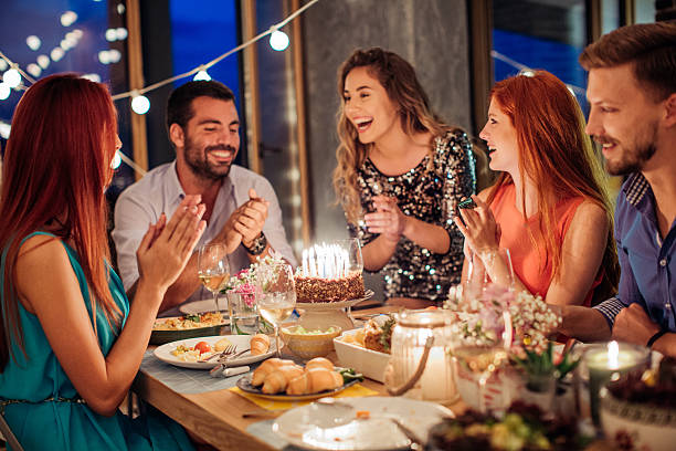 Friends and family gather around a table, enjoying a birthday meal together.